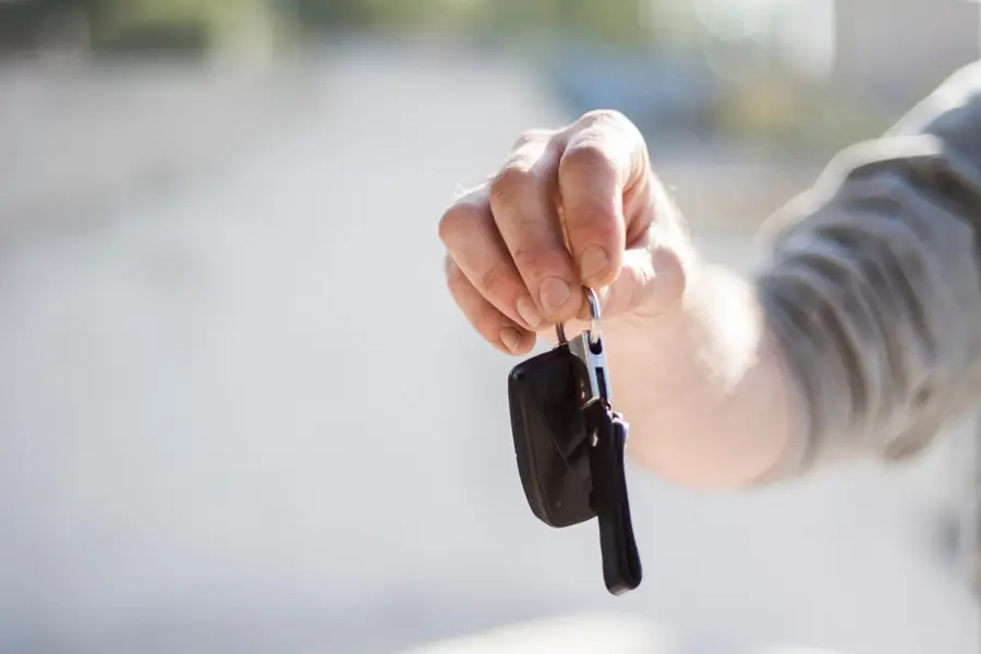 A hand holding out a car key