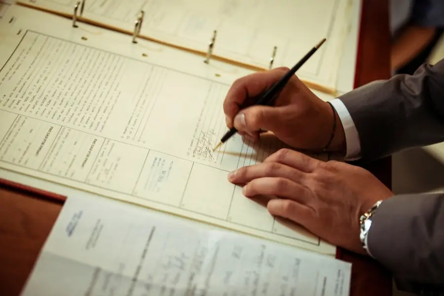Hands signing paperwork at a desk